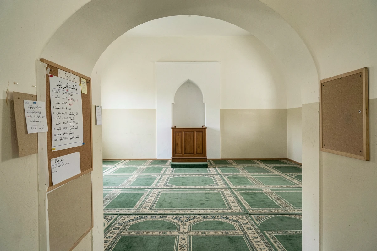 Intérieur d'une salle de prière d'une mosquée avec tableau des horaires à Mons-en-Barœul