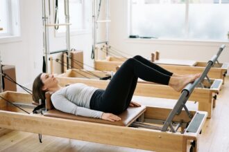 Femme réalisant un exercice de leg press sur un Reformer Pilates dans un studio élégant au design épuré style parisien